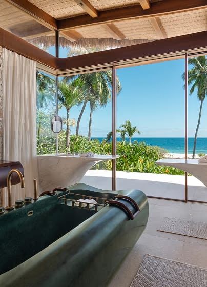 A villa bathroom with a freestanding stone bathtub facing the ocean