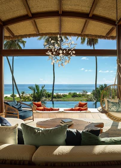 An open-plan villa lounge with deep sofas and ocean views through floor-to-ceiling glass